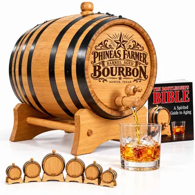 Personalized American white oak bourbon aging barrel with Phineas Farmer engraving, black steel hoops, wooden spigot, stand, whiskey glass, and Bootlegger's Bible booklet.